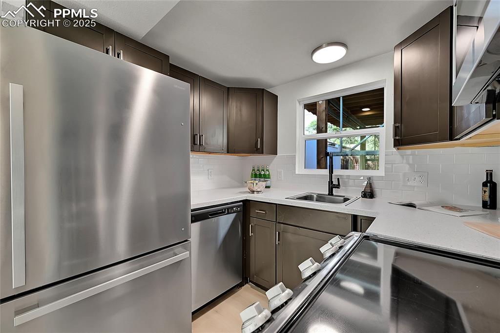 Image 12 of 29: Kitchen with stainless steel appliances, light stone counters, tasteful bac