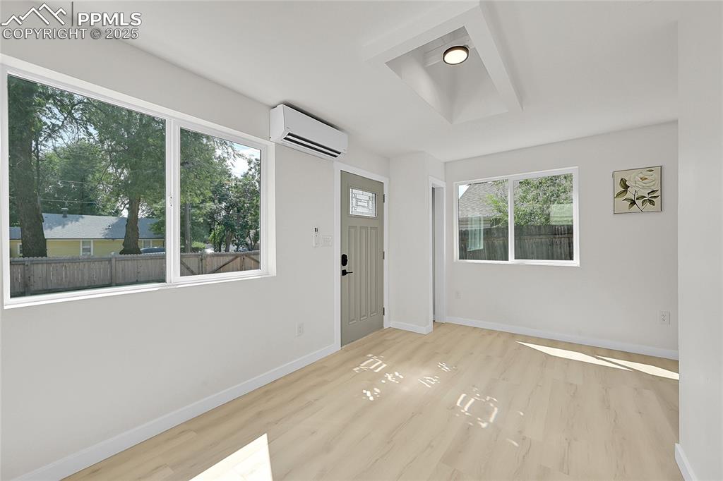 Image 2 of 29: Entryway with light wood finished floors and a wall unit AC