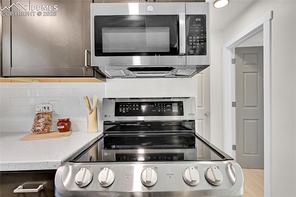 Image 4 of 29: Kitchen featuring appliances with stainless steel finishes, light stone cou