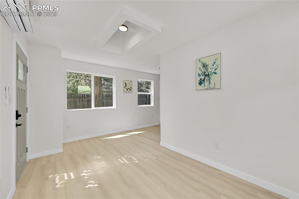 Image 7 of 29: Empty room with an AC wall unit and light wood-style flooring