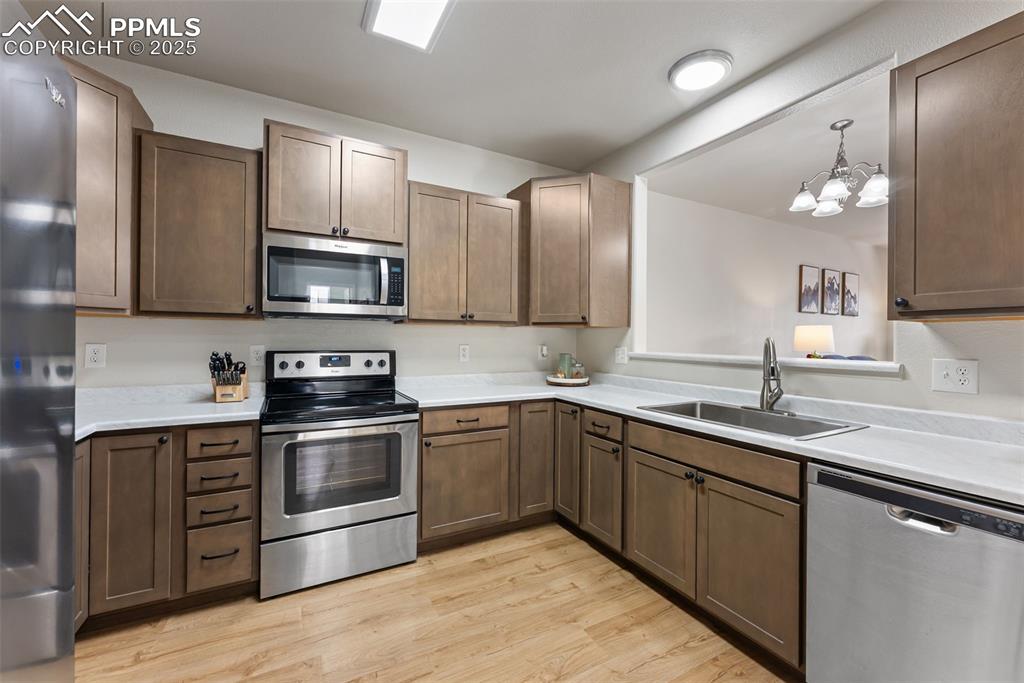 Image 10 of 34: Kitchen with stainless steel appliances, light wood-style floors, light cou