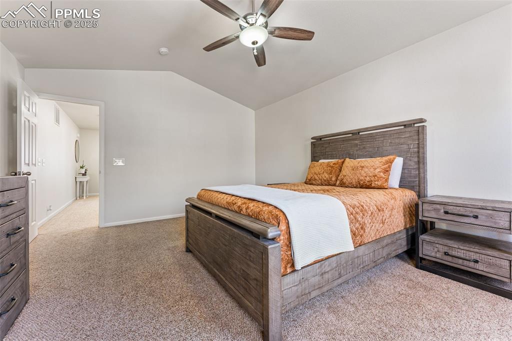 Image 23 of 34: Carpeted bedroom featuring vaulted ceiling and a ceiling fan