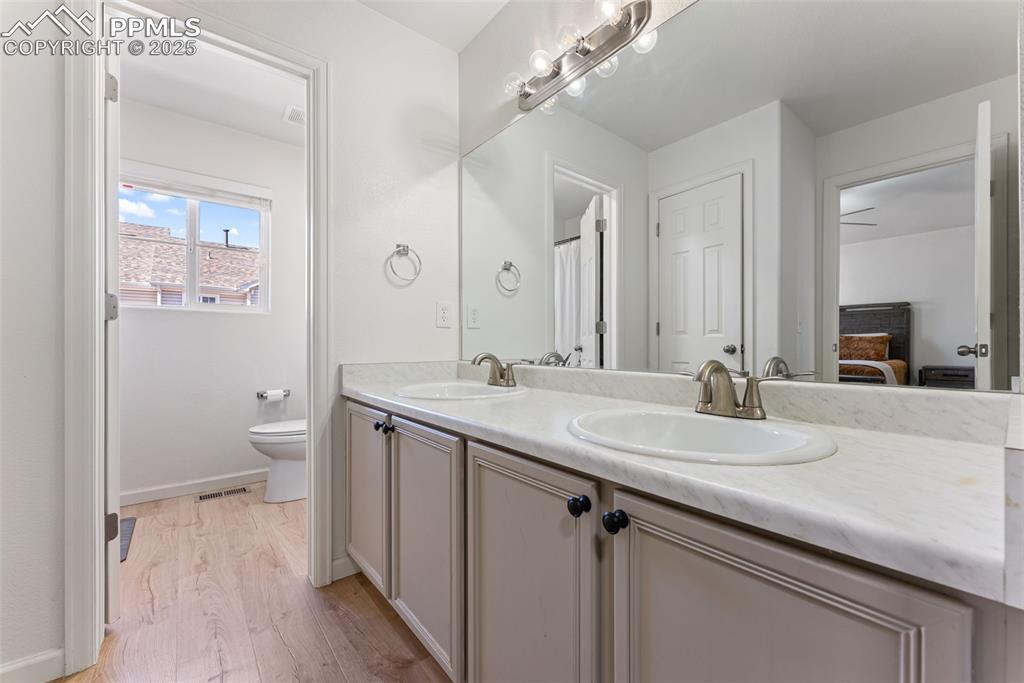 Image 25 of 34: Ensuite bathroom with light wood-style flooring and double vanity