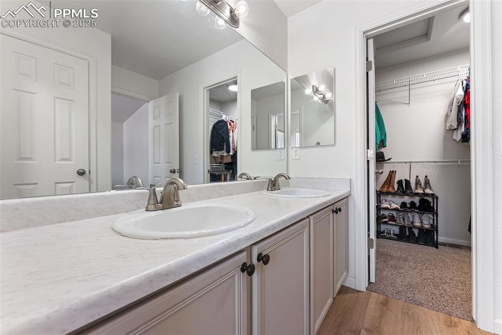 Image 26 of 34: Bathroom with a spacious closet, light wood-style flooring, and double vani