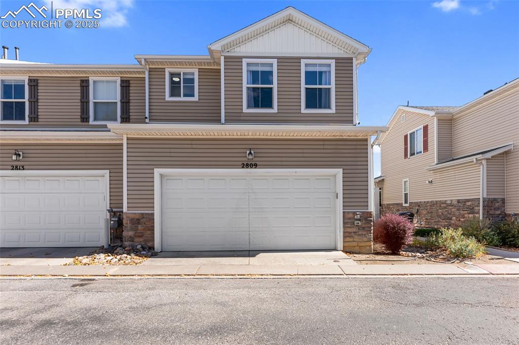 Image 28 of 34: View of front of home with stone siding and an attached garage