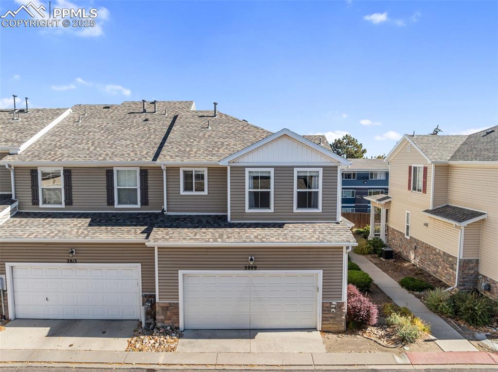 Image 29 of 34: View of front of house with a shingled roof, an attached garage, and concre