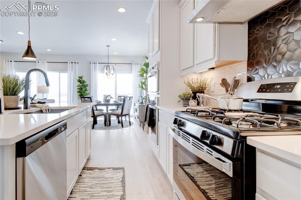 Image 12 of 32: Kitchen with recessed lighting, range hood, light countertops, a sink, and 