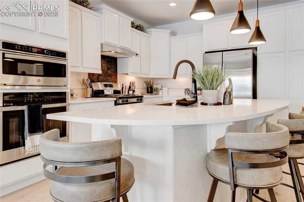 Image 14 of 32: Kitchen with stainless steel appliances, under cabinet range hood, a sink, 