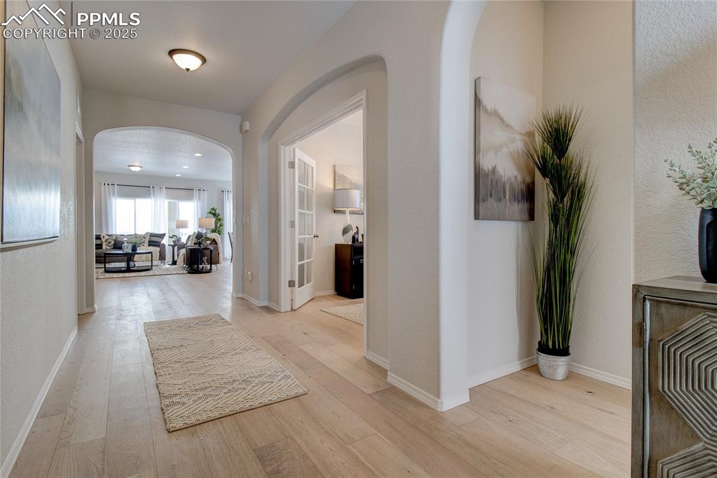 Image 2 of 32: Hall with arched walkways and light wood finished floors