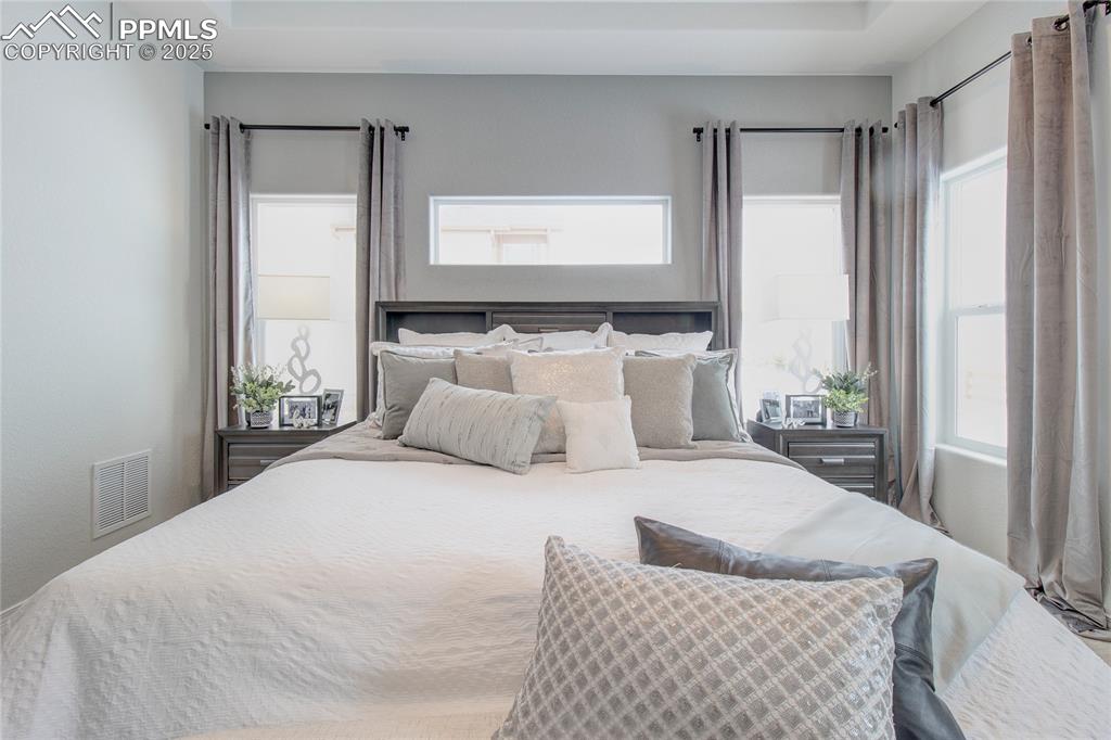 Image 21 of 32: Bedroom with visible vents and a tray ceiling
