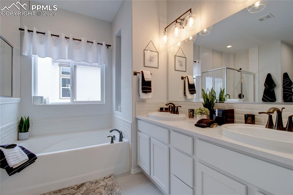 Image 22 of 32: Bathroom with visible vents, a sink, a shower stall, and double vanity