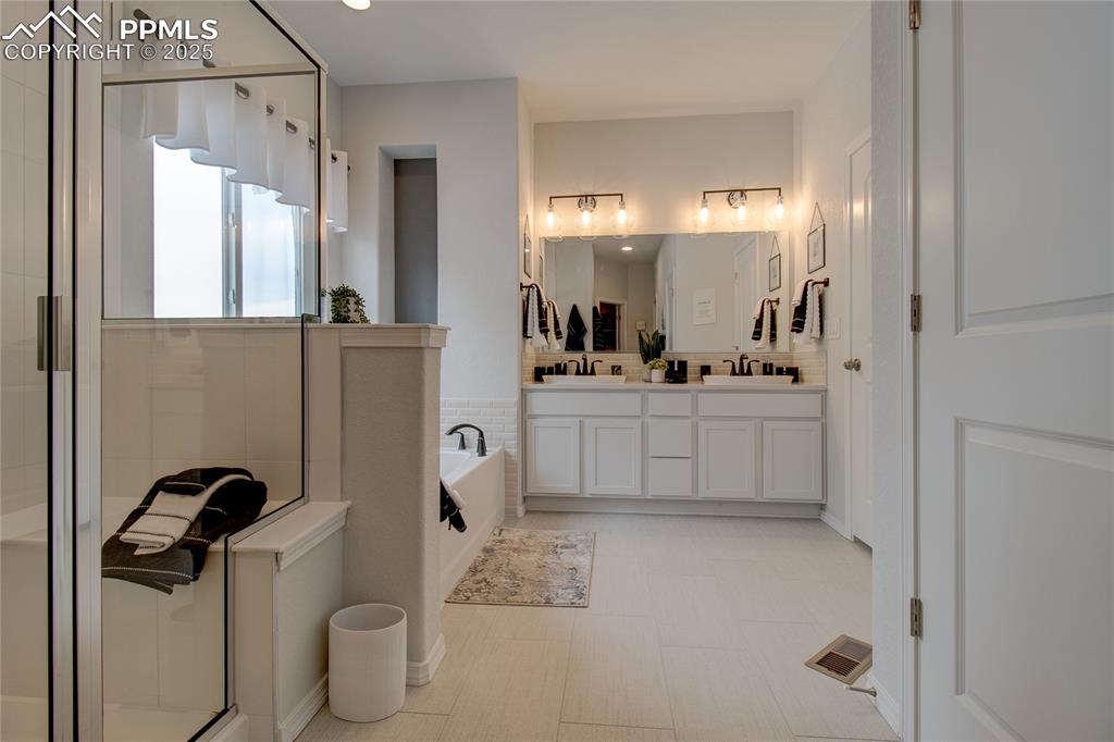 Image 23 of 32: Bathroom featuring double vanity, visible vents, a sink, a garden tub, and 
