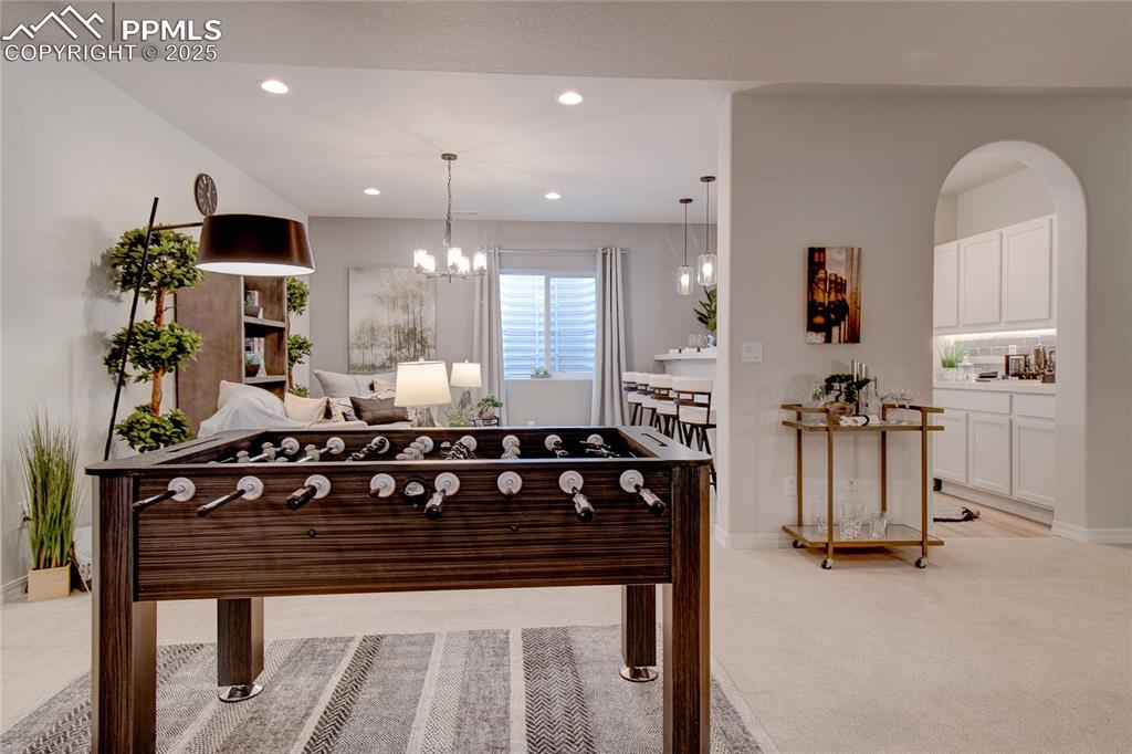 Image 31 of 32: Playroom with baseboards, light carpet, an inviting chandelier, and recesse