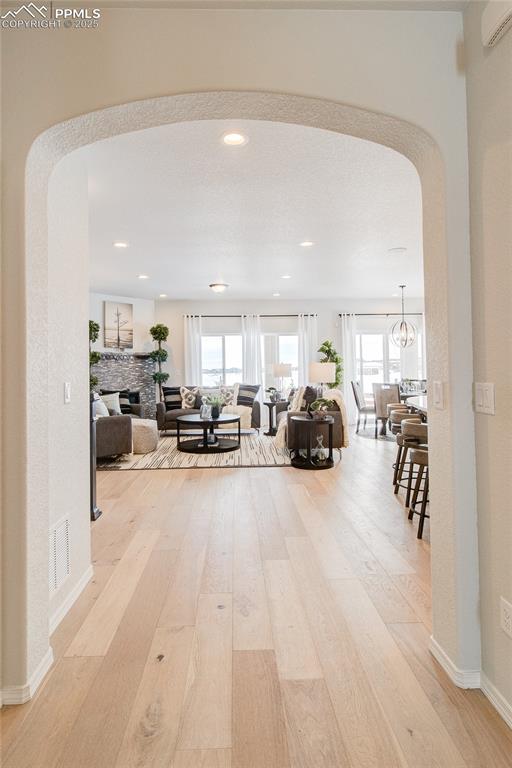 Image 5 of 32: Hall with an AC wall unit, wood finished floors, visible vents, and arched 