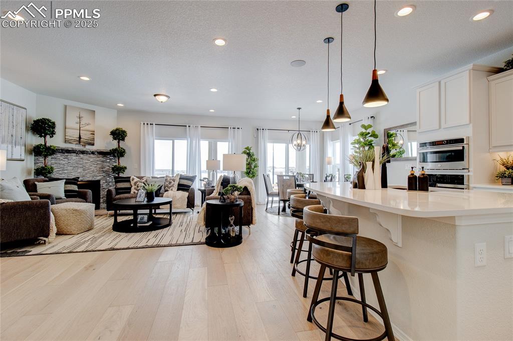 Image 8 of 32: Kitchen with a breakfast bar area, open floor plan, white cabinetry, and li
