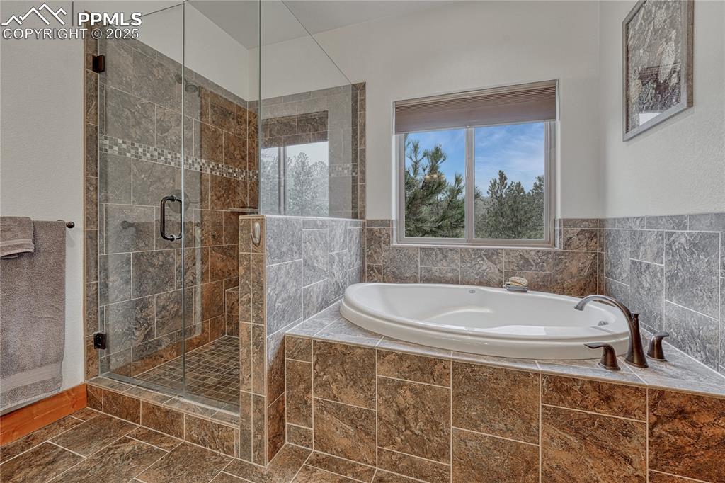 Image 25 of 43: Bathroom featuring a garden tub and a shower stall