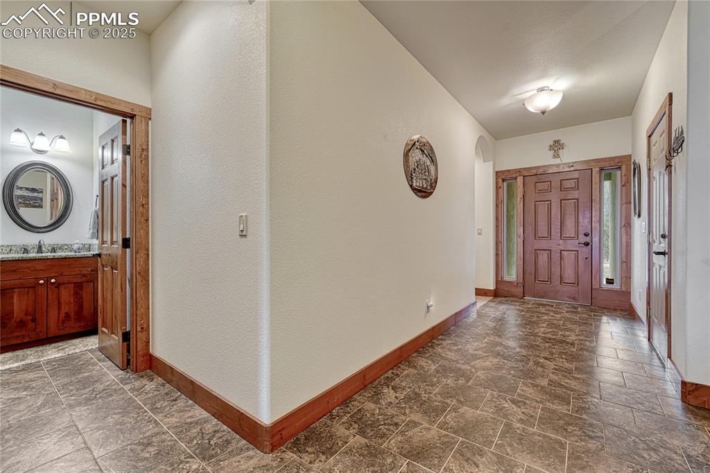 Image 3 of 43: Foyer with baseboards, dark stone finish floors, and a textured wall