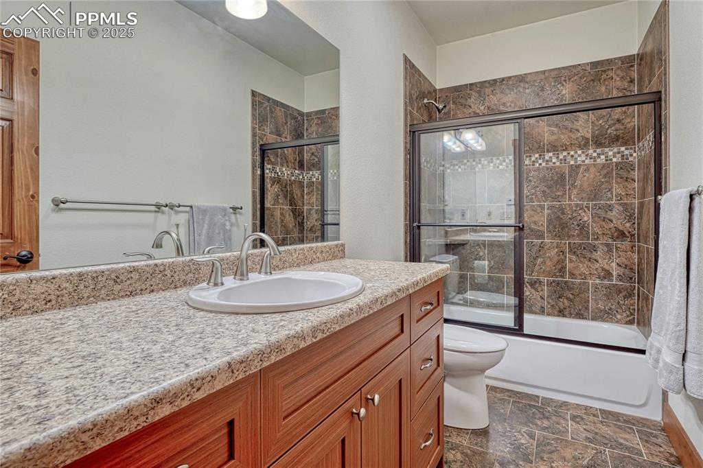 Image 34 of 43: Bathroom featuring toilet, vanity, combined bath / shower with glass door,