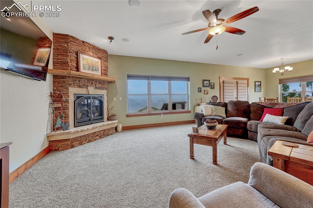 Image 4 of 43: Living room featuring a stone fireplace, a chandelier, baseboards, and carp