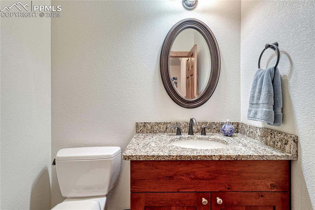 Image 41 of 43: Half bathroom with vanity, toilet, and a textured wall