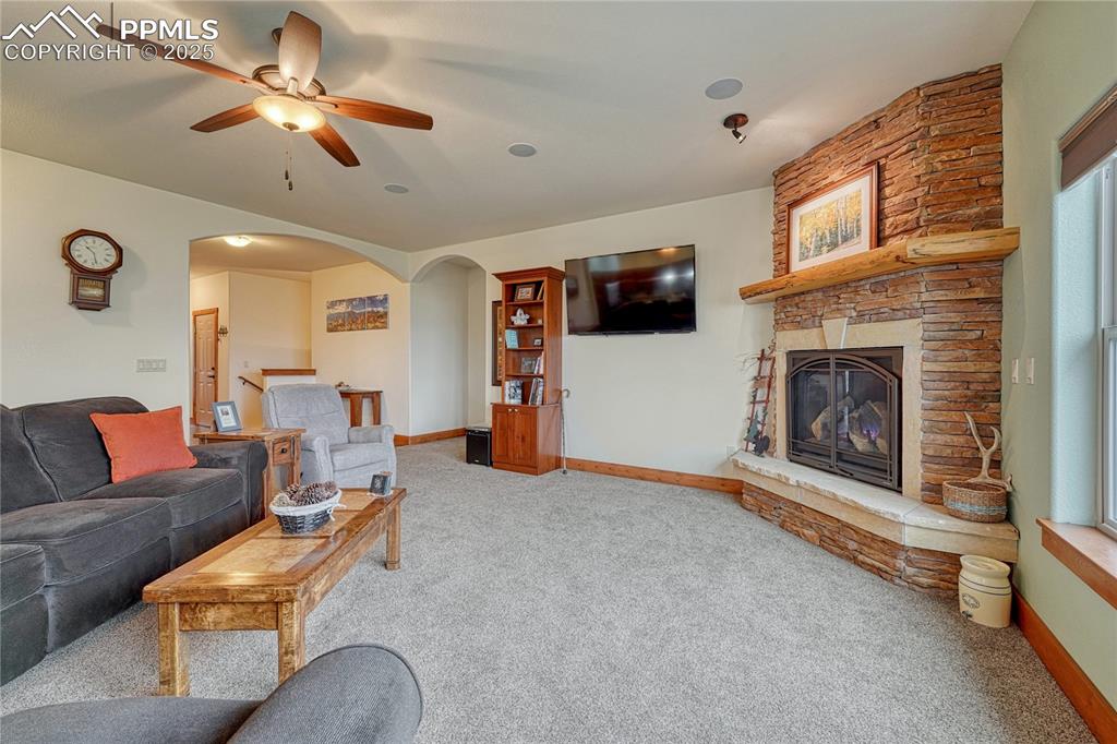 Image 5 of 43: Living room featuring carpet floors, arched walkways, a ceiling fan, a ston