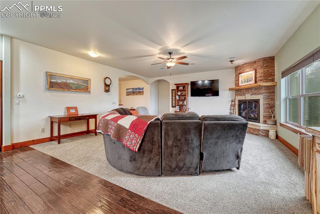 Image 6 of 43: Living room featuring arched walkways, a ceiling fan, baseboards, a stone f