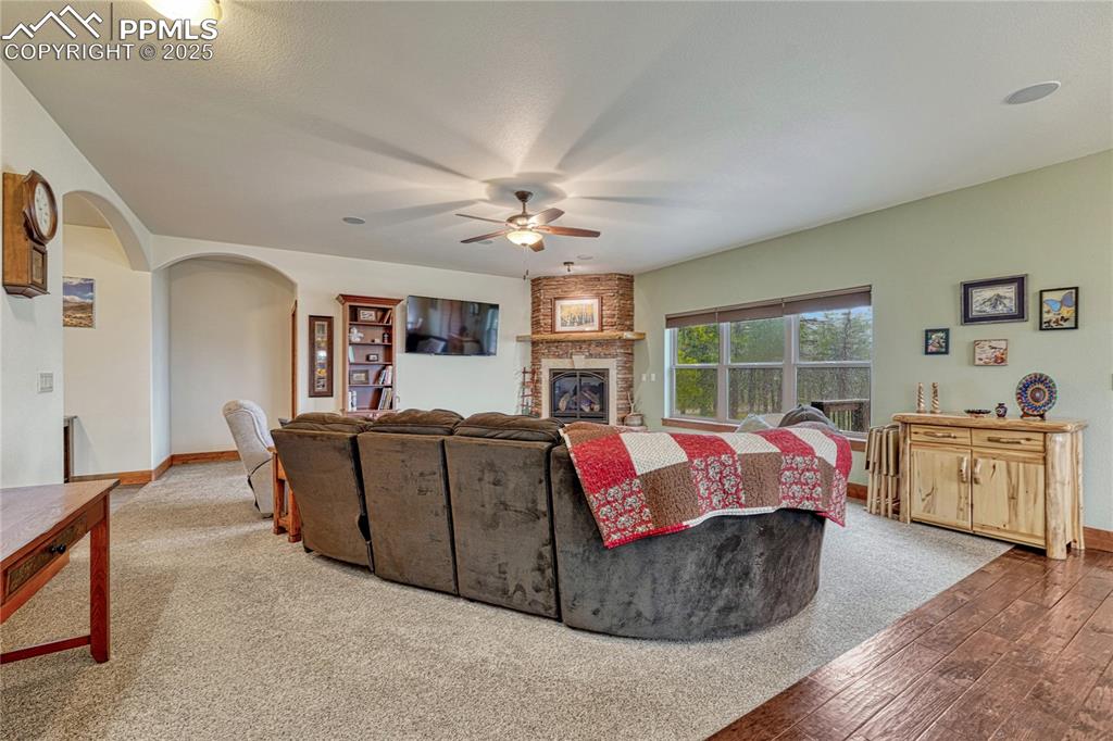 Image 7 of 43: Living area with ceiling fan, arched walkways, a fireplace, hardwood / wood