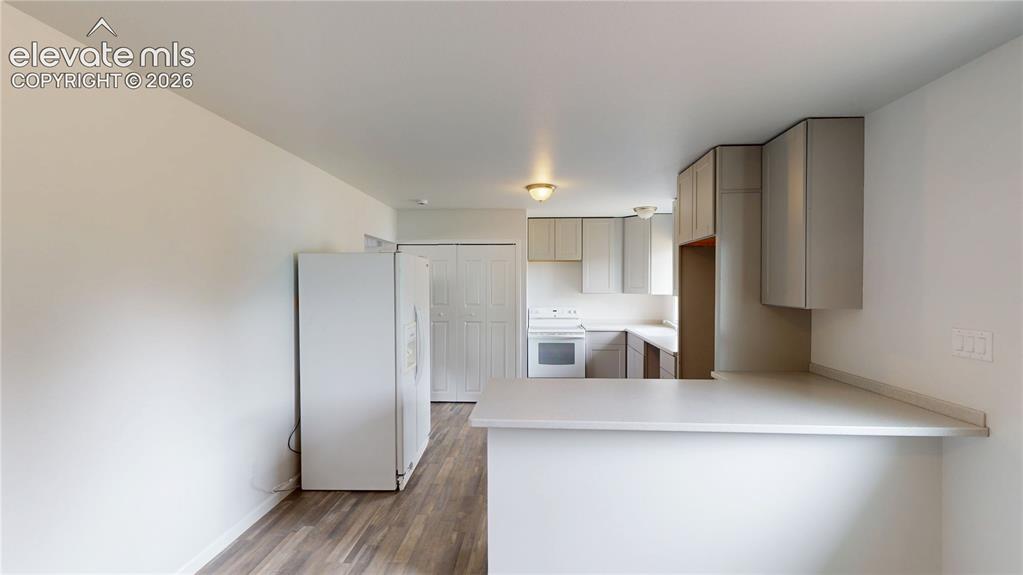 Image 4 of 16: Kitchen area featuring wood-finish flooring, white appliances, light-toned 