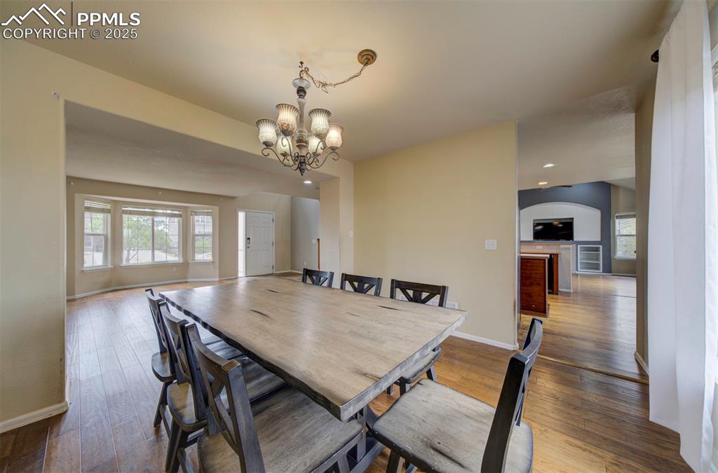 Image 10 of 43: Dining room with a chandelier, baseboards, wood finished floors, and arched