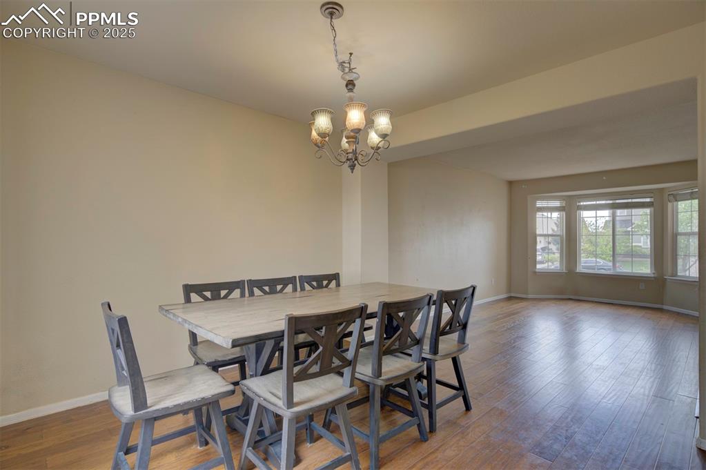 Image 11 of 43: Dining space featuring baseboards, a chandelier, and wood finished floors