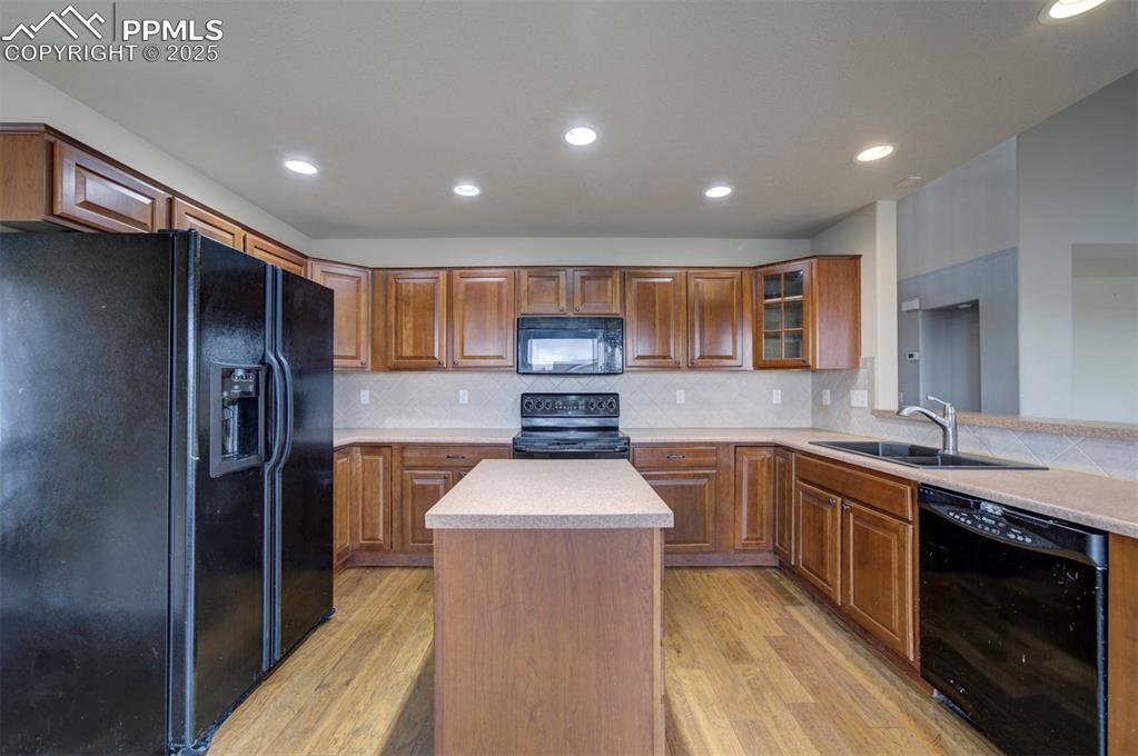 Image 12 of 43: Kitchen with black appliances, a sink, light wood-style floors, light count