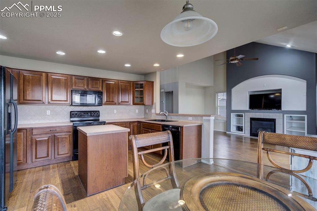 Image 15 of 43: Kitchen with black appliances, hardwood / wood-style flooring, a peninsula,