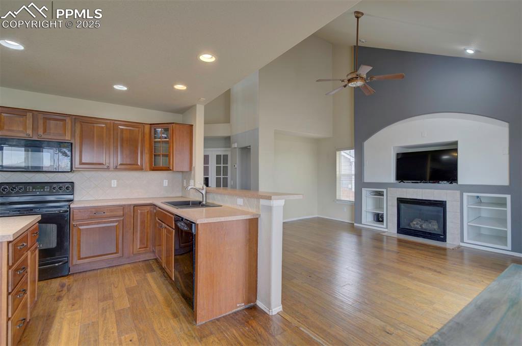 Image 17 of 43: Kitchen featuring black appliances, a peninsula, a sink, light countertops,
