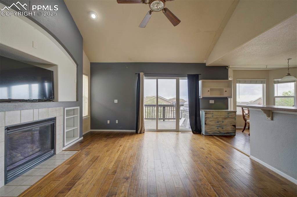 Image 18 of 43: Unfurnished living room featuring ceiling fan, a tile fireplace, baseboards