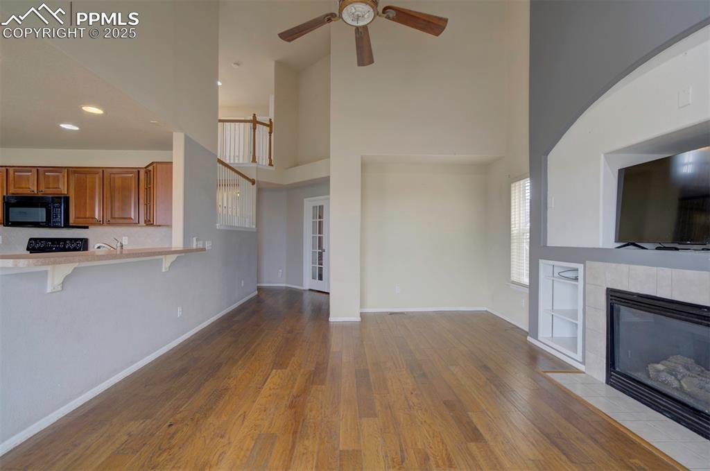 Image 19 of 43: Unfurnished living room with a high ceiling, ceiling fan, wood finished flo