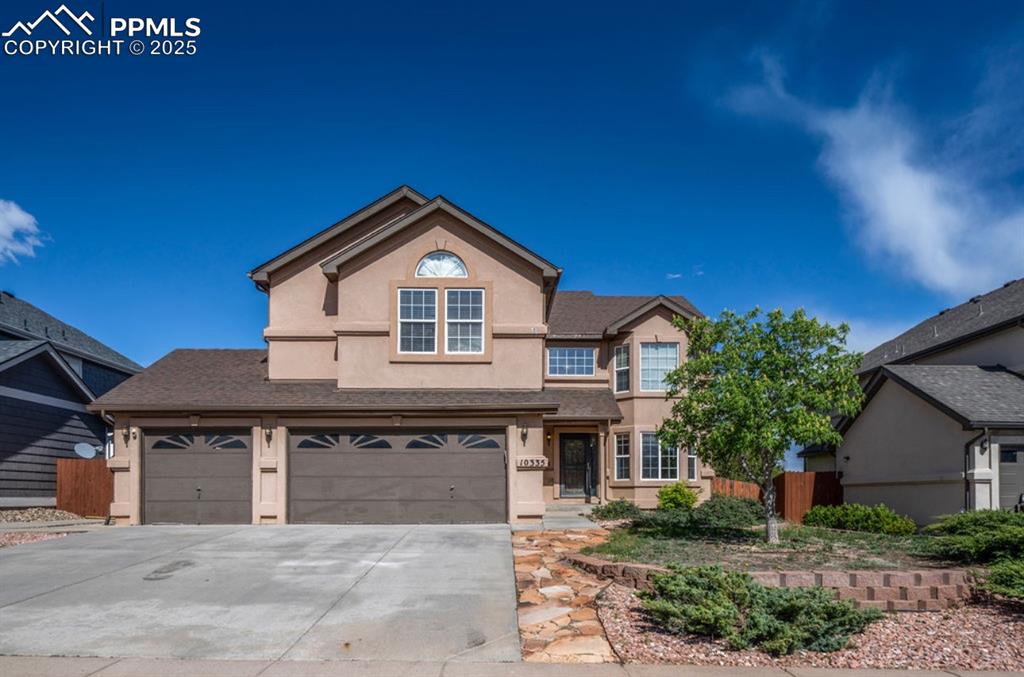 Image 2 of 43: Traditional home featuring stucco siding, driveway, and a garage