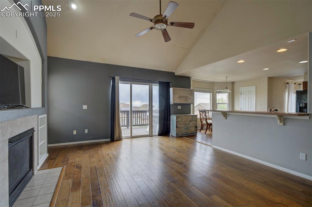 Image 22 of 43: Unfurnished living room featuring a ceiling fan, a tile fireplace, high vau
