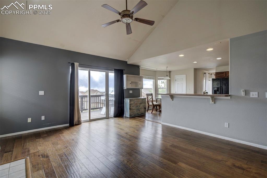 Image 23 of 43: Unfurnished living room featuring ceiling fan, high vaulted ceiling, basebo