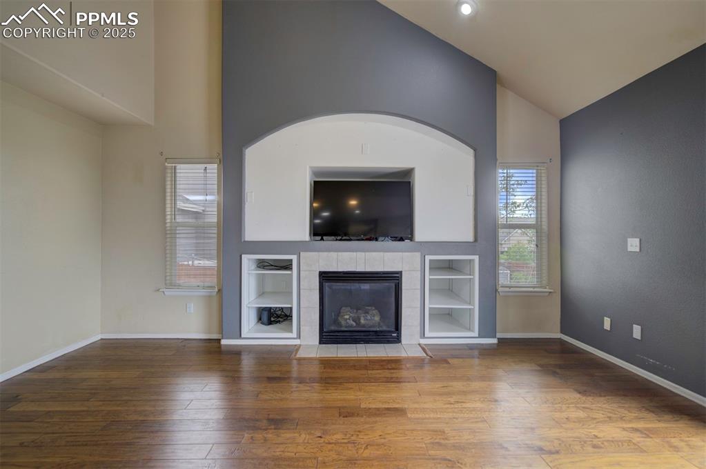 Image 24 of 43: Unfurnished living room featuring wood finished floors, high vaulted ceilin