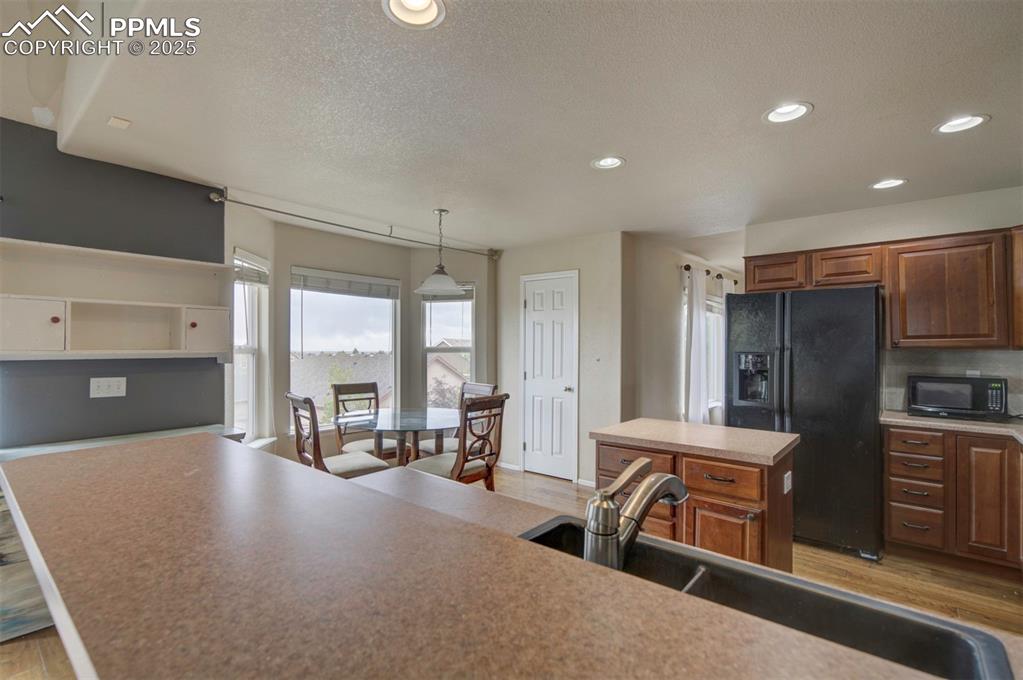Image 25 of 43: Kitchen with black appliances, a sink, light wood-style flooring, recessed