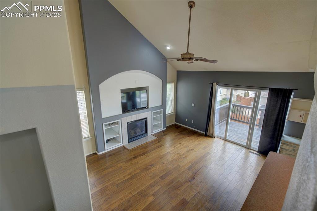 Image 27 of 43: Unfurnished living room featuring a fireplace, high vaulted ceiling, hardwo