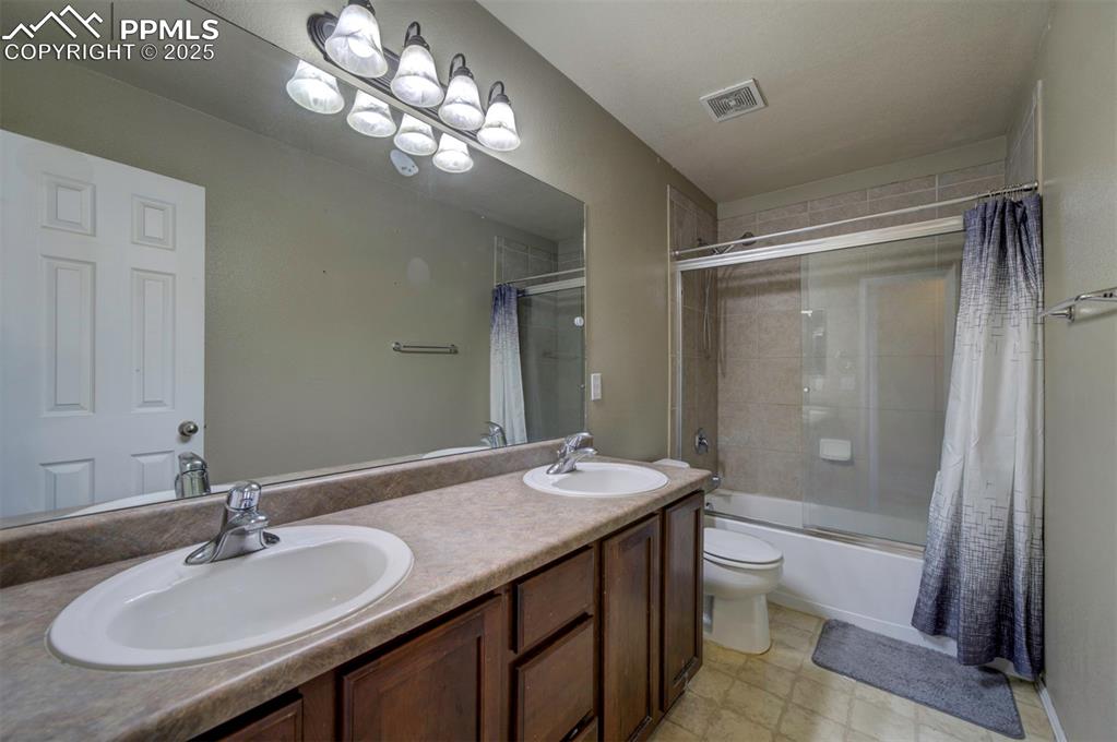 Image 28 of 43: Bathroom with bath / shower combo with glass door, double vanity, and toile