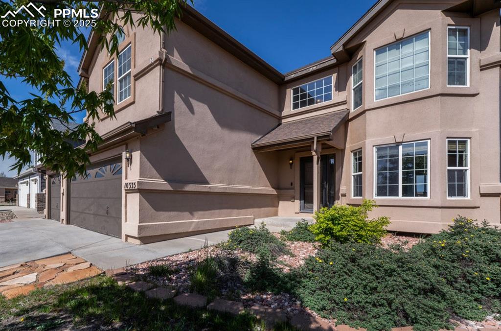 Image 3 of 43: View of front of property with stucco siding, a garage, and concrete drivew