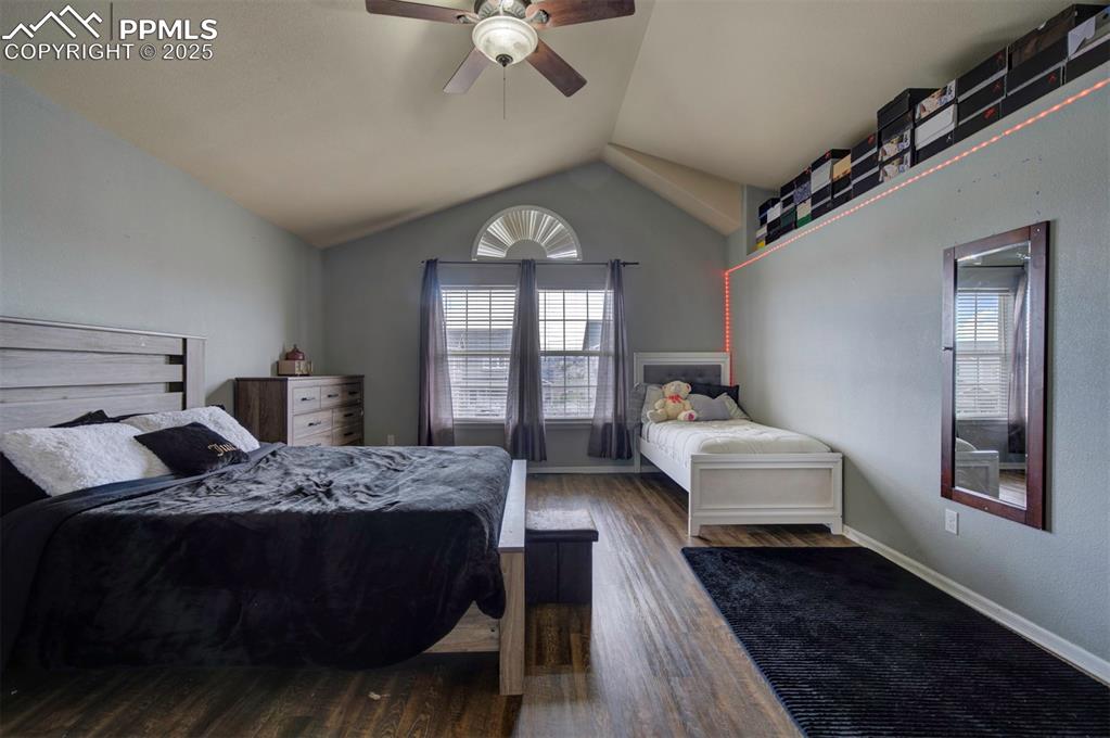 Image 40 of 43: Bedroom with wood finished floors, vaulted ceiling, ceiling fan, and basebo