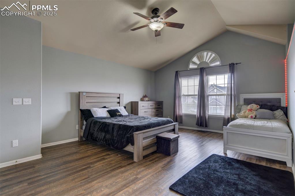 Image 41 of 43: Bedroom with vaulted ceiling, wood finished floors, ceiling fan, and basebo