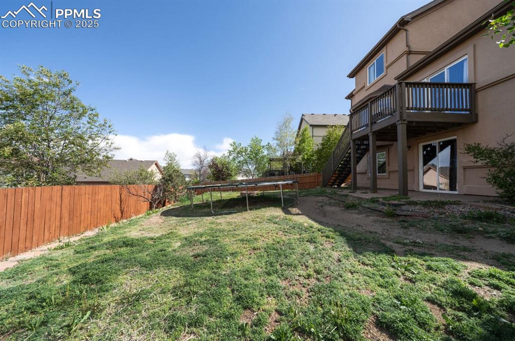 Image 43 of 43: View of yard featuring a trampoline, stairway, and a wooden deck