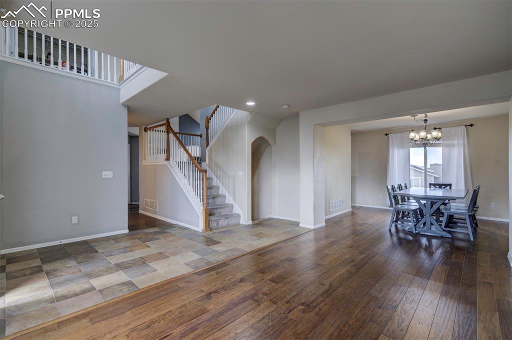 Image 5 of 43: Unfurnished living room with arched walkways, stairway, wood-type flooring,