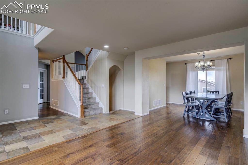 Image 6 of 43: Unfurnished dining area with stairway, wood-type flooring, a chandelier, ba