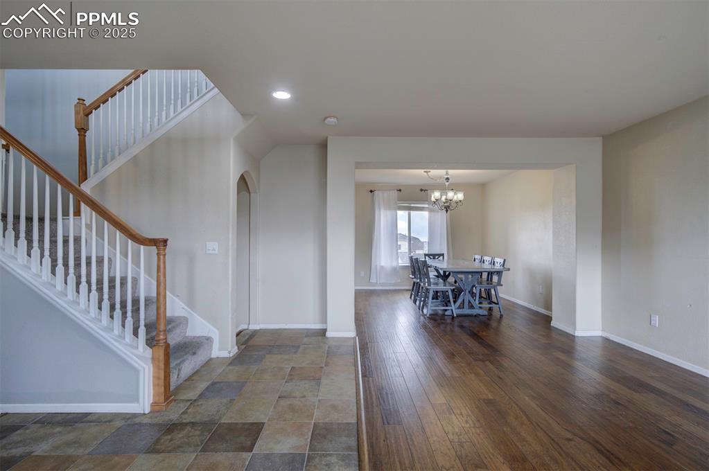 Image 7 of 43: Foyer entrance with arched walkways, baseboards, stairway, a chandelier, an