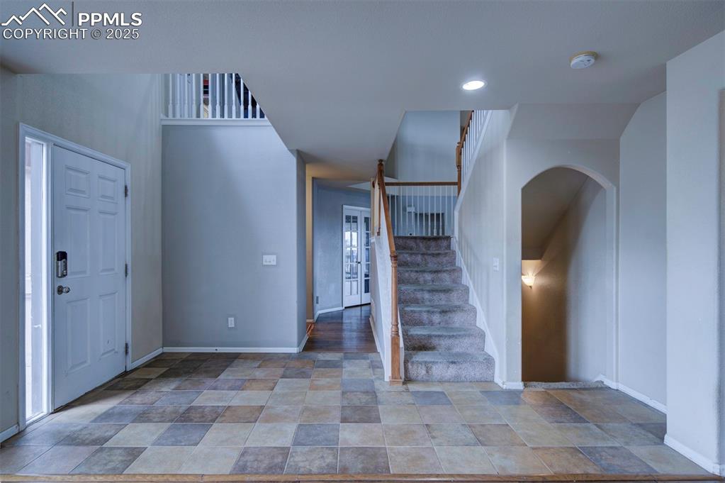 Image 8 of 43: Foyer with stairs, baseboards, stone finish floors, and recessed lighting